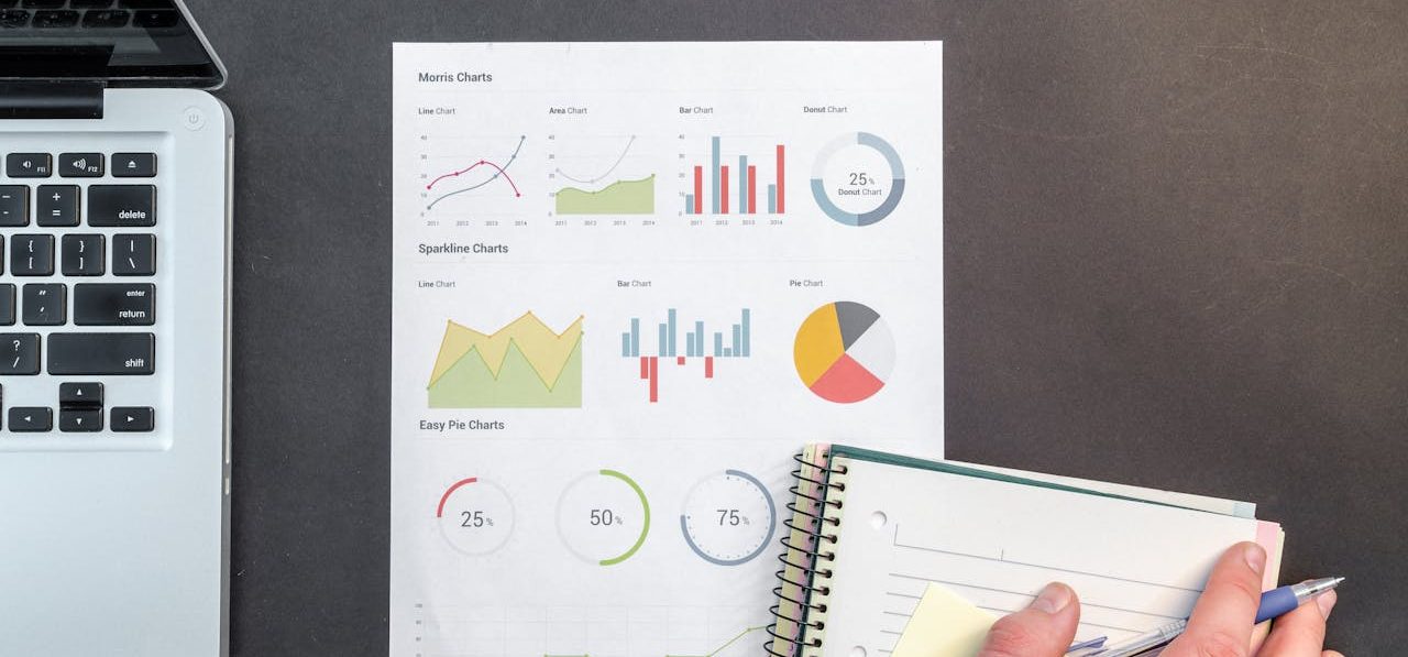 Overhead view of a business desk with charts and a laptop, ideal for data analysis concepts.